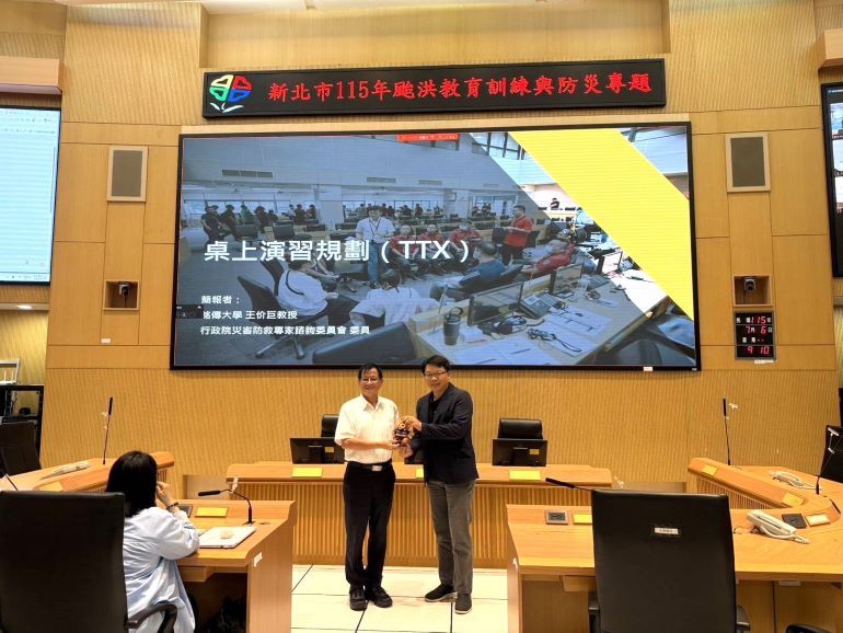 《圖說》消防局長陳崇致贈宣導品予銘傳大學王价巨教授。〈消防局提供〉