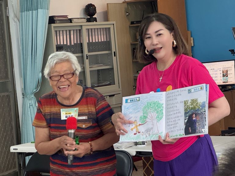 八旬長輩畫出人生彩虹 阿公〈我愛你〉阿嬤羞紅臉 7 《圖說》羅李屘阿嬤(左)在生命繪本中畫出里長幫忙鋸家門前的大樹。〈社會局提供〉
