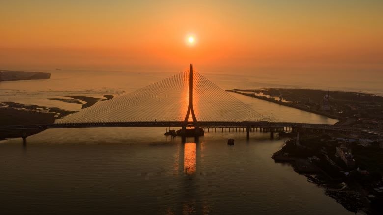 台北夏季旅展7/17登場 新北館6業者推優惠手作DIY吸客 7 《圖說》淡水河口的金黃夕照與宏偉的淡江大橋巧妙相遇,橋塔的俐落剪影與波光 粼粼的水面勾勒出專屬淡八地區的嶄新觀光地標。〈觀旅局提供〉