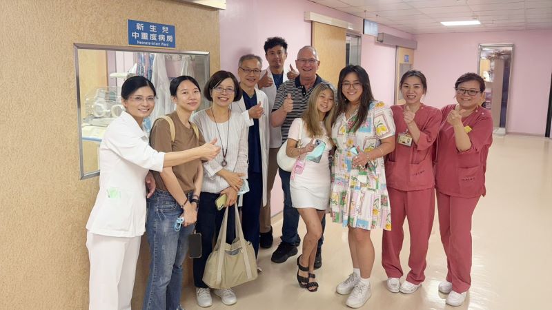 《圖說》Emily(右4)在養父(右5)與姊姊(右3)及新北社會局人員(左2、左3)陪同下，來到臺北醫院。〈臺北醫院提供〉